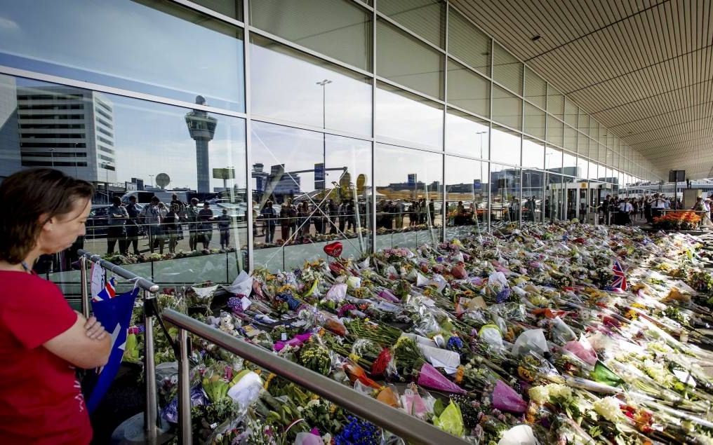 Een vrouw kijkt naar de talloze bloemen die op Schiphol zijn achtergelaten ter gedachtenis aan de slachtoffers van de vliegramp in Oekraïne. Beeld EPA