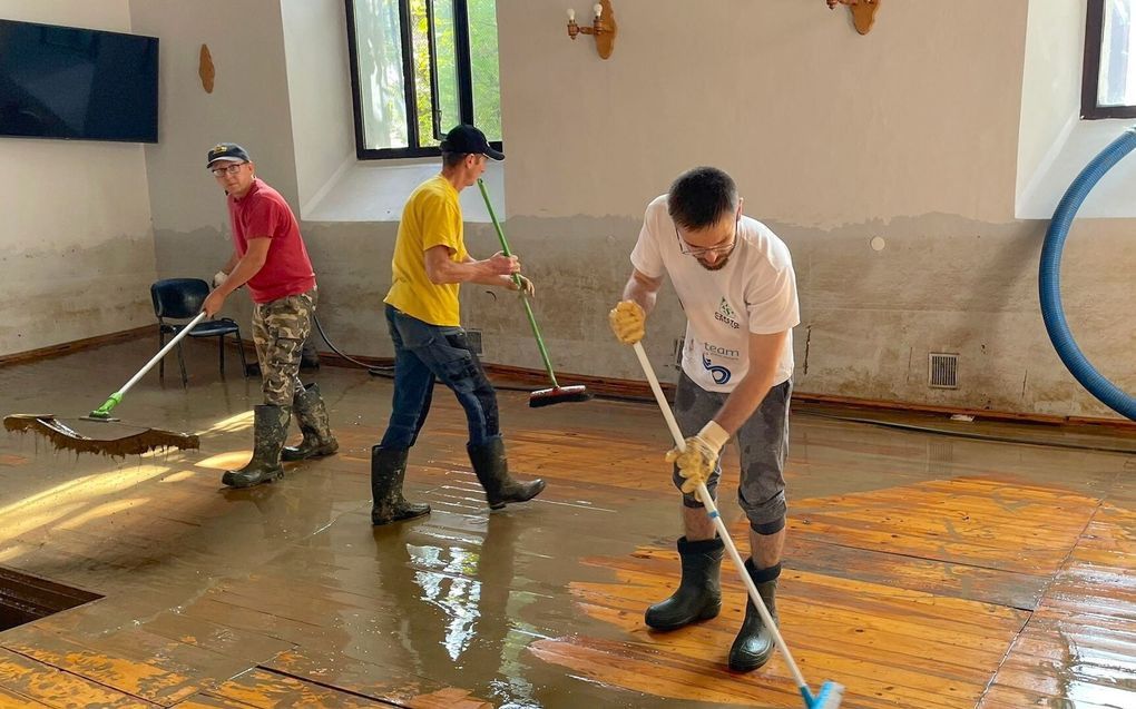 Leden van een kerkelijke gemeente in het Poolse Nysa maken de vloer van hun kerkgebouw schoon. beeld EPA, Slawek Pabian