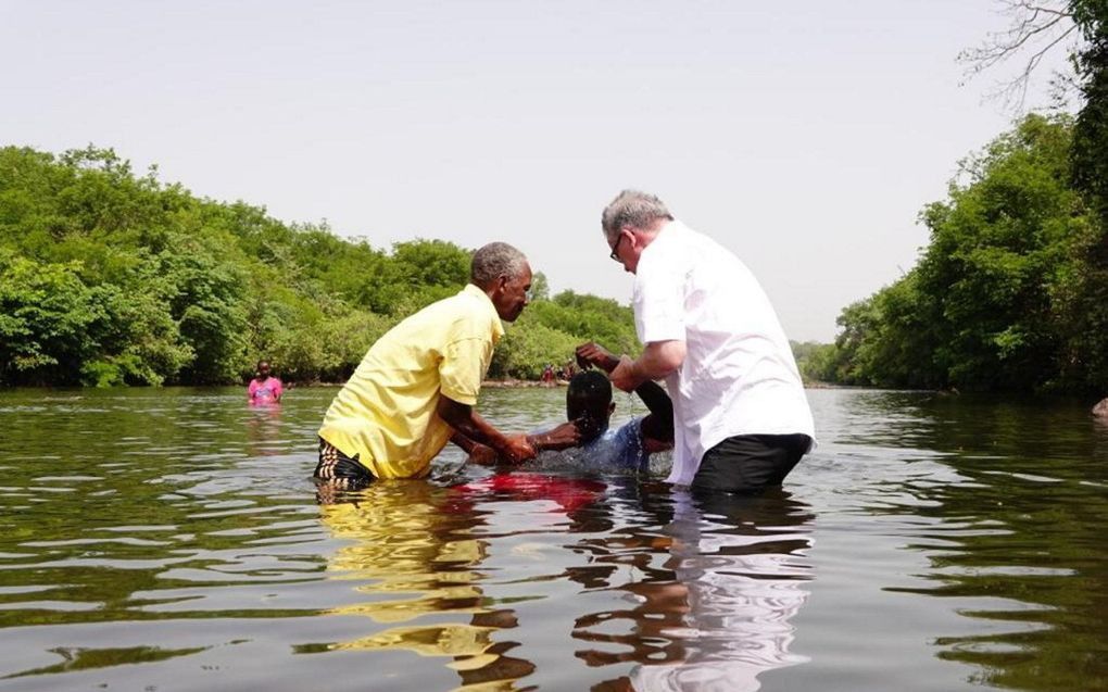 Hoe aan te kijken tegen het uitzenden van zendingswerkers? Foto: ds. J.B. Zippro, predikant van de Gereformeerde Gemeenten en de Guineese christen Gabriel verrichten, maart 2022, de Heilige Doop in een rivier in Guinee. beeld ZGG