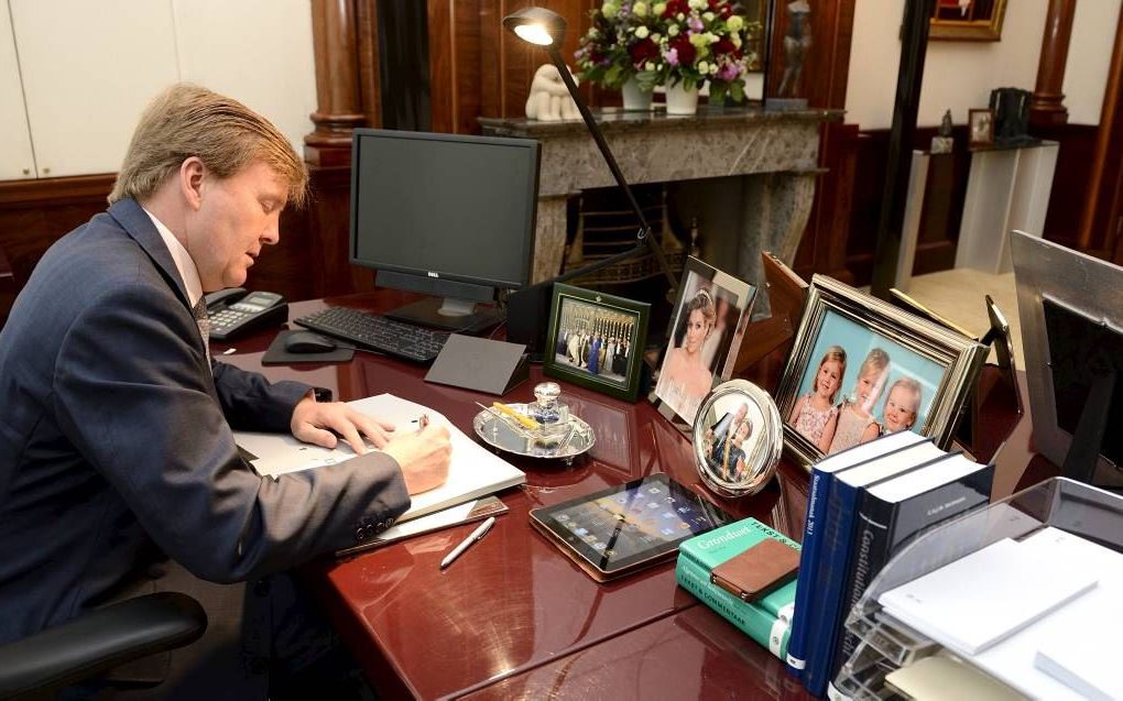 Koning Willem-Alexander zet in zijn werkkamer in paleis Noordeinde zijn handtekening onder een aantal wetten. beeld ANP