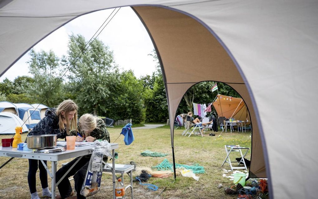 Jonge kampeerders vermaken zich bij hun tent op een natuurcamping van Staatsbosbeheer op Terschelling. beeld ANP, Sem van der Wal
