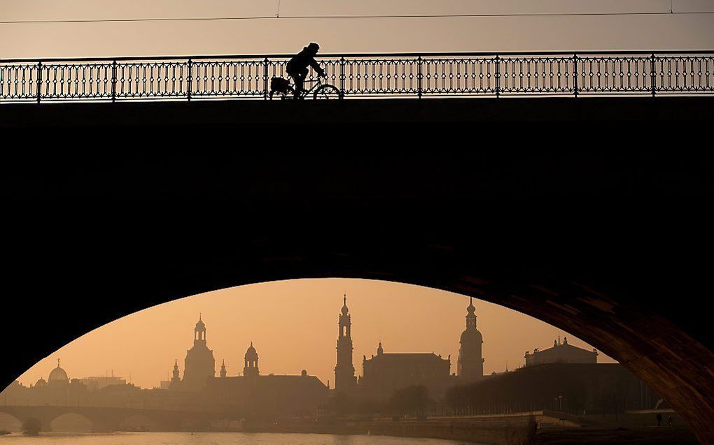 Een fietser is maandagochtend bij zonsopkomst onderweg in het Duitse Dresden. beeld EPA