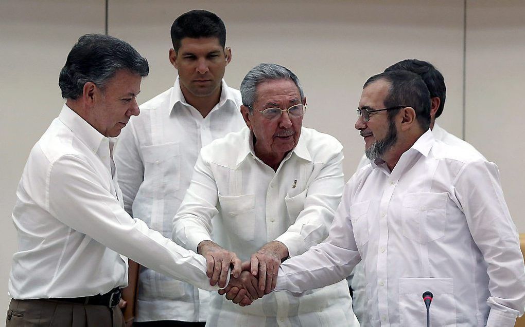 De Cubaanse president Castro (m.) schudt de handen van de Colombiaanse president Santos (l). en FARC-leider Londono. Beeld EPA