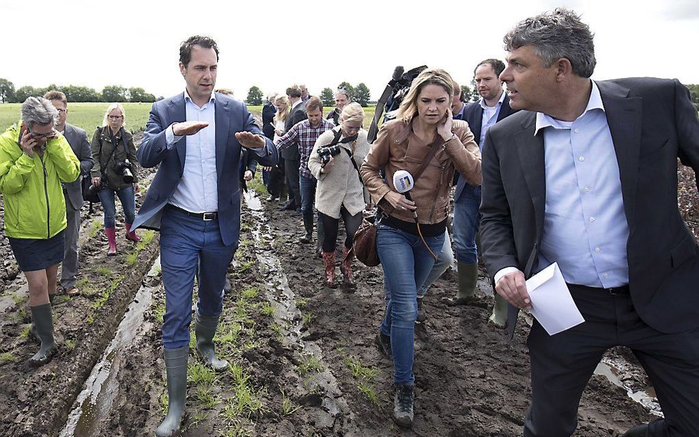 Staatssecretaris Van Dam (l.) bekijkt de waterschade op een bedrijf in Limburg. beeld ANP, Marcel van Hoorn