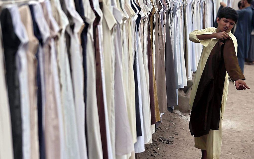 Een Pakistaan probeert kleding. Veel moslims kopen nieuwe kleding en cadeaus als voorbereiding op het suikerfeest, de afsluiting van de Ramadan. beeld EPA