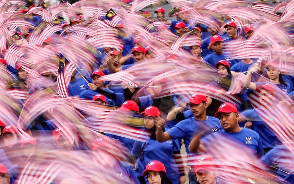 Inwoners van Maleisië wuiven met de vlag op mars op de nationale onafhankelijkheidsdag. beeld EPA