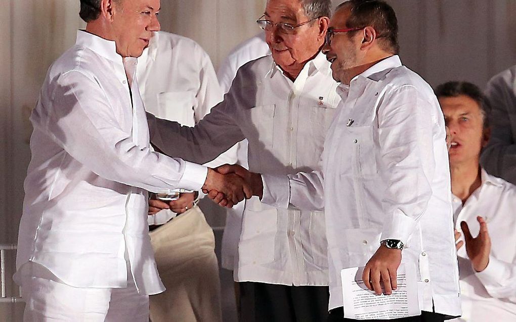 De Colombiaanse president Santos (l.) schudt de hand van FARC-leider Rodrigo Londono Echeverri (r.). De Cubaanse president Raul Castro (m.) kijkt toe.  beeld EPA, Mauricio Duenas Castaneda