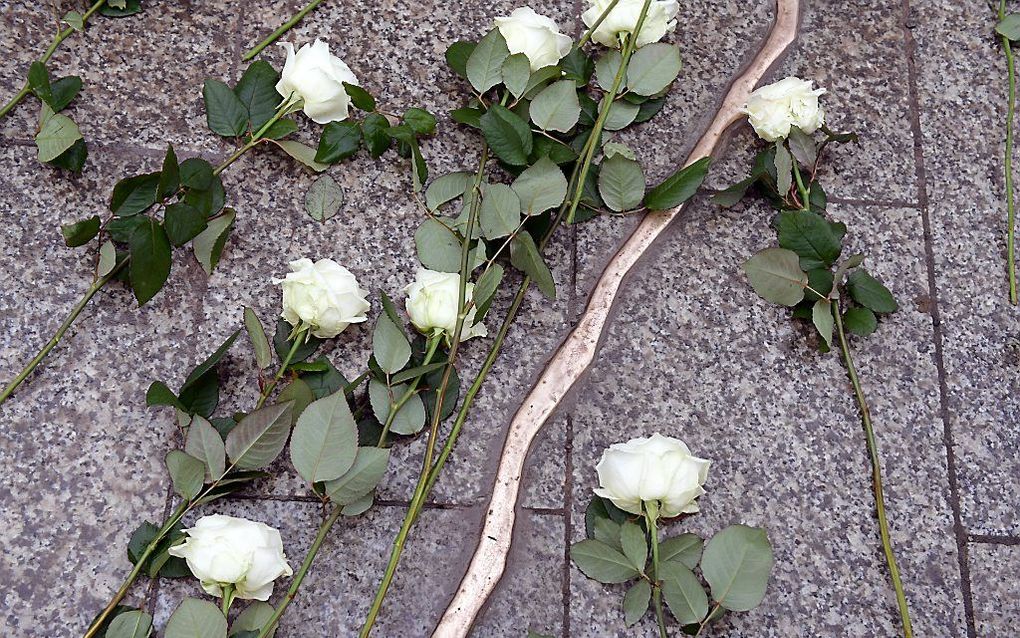 Witte rozen bij de gouden ‘barst’ in de grond die de diepe wond moet symboliseren die de aanslag bij de getroffenen veroorzaakte. beeld EPA