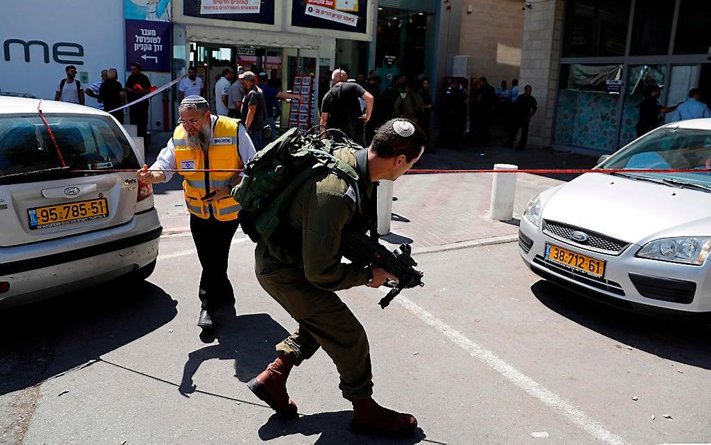 Israëlische veiligheidsdiensten inspecteren de plaats waar zondag de Israëliër Ari Fuld door een Palestijnse tiener werd doodgestoken. beeld AFP, Ahmad Gharabli