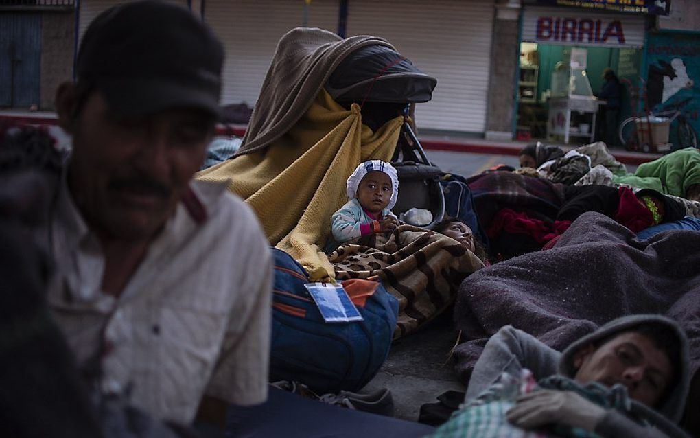 Een groep Hondurezen zit op straat in Tijuana. beeld AFP