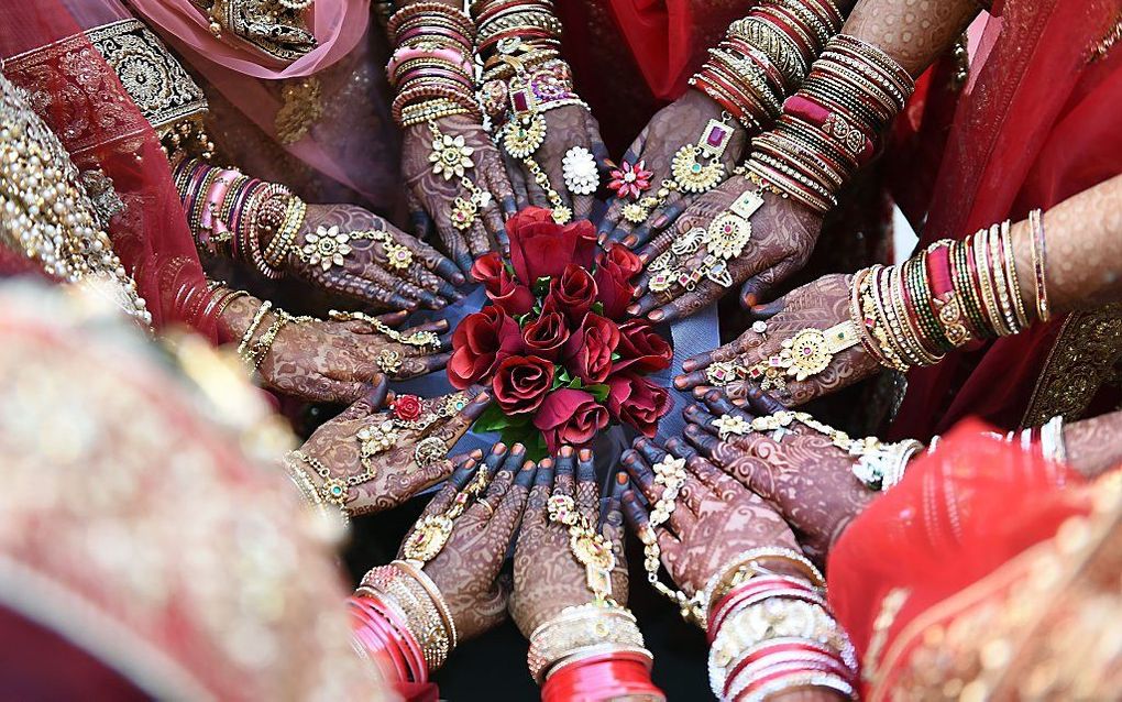 Deelneemsters aan een massahuwelijk poseren voor de camera in het Indiase Surat. beeld AFP