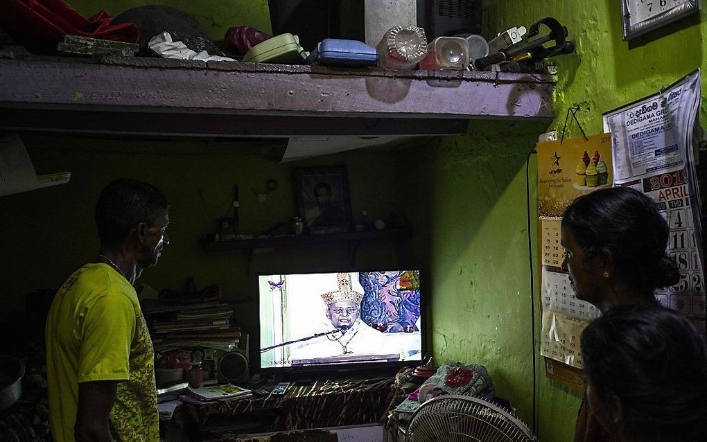 Katholieke Sri Lankanen kijken op afstand naar de mis die alleen via tv wordt uitgezonden. beeld AFP, Jewel Samad