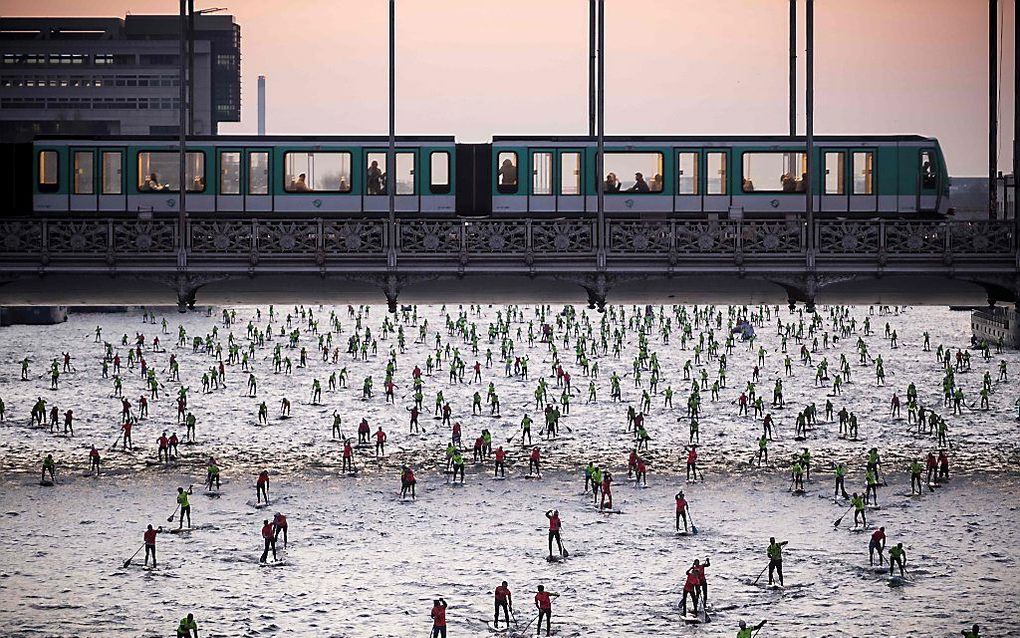 Peddelen over de Seine in Parijs tijdens de 7de editie van de Nautic SUP Paris Crossing. beeld AFP