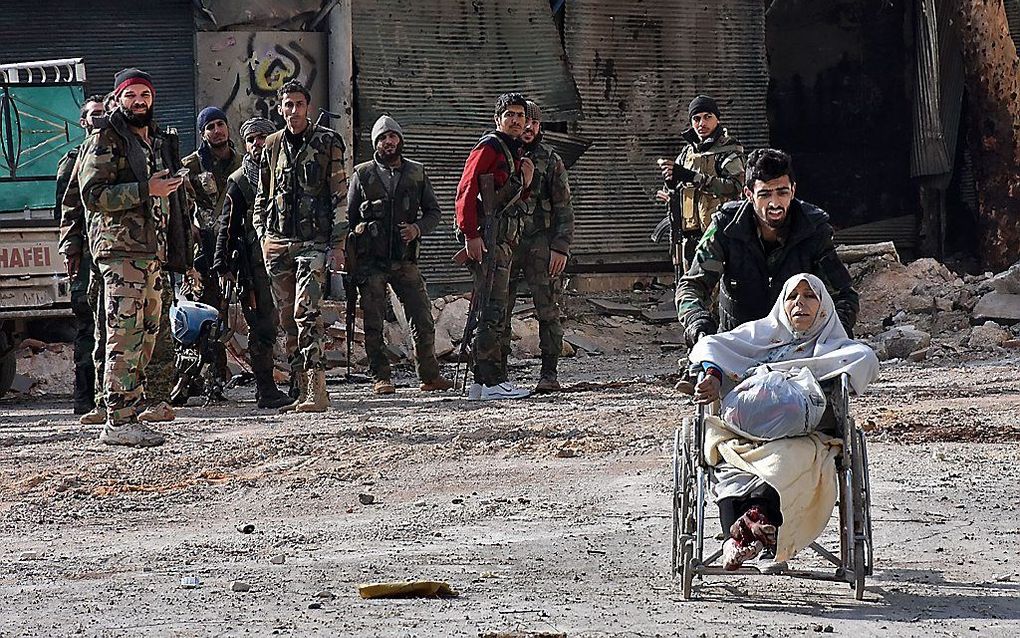 ALEPPO. Een soldaat van het Syrische leger in Aleppo reed gisteren  een invalide vrouw weg uit een wijk die zojuist door het leger is heroverd op rebellen. beeld AFP, George Ourfalian