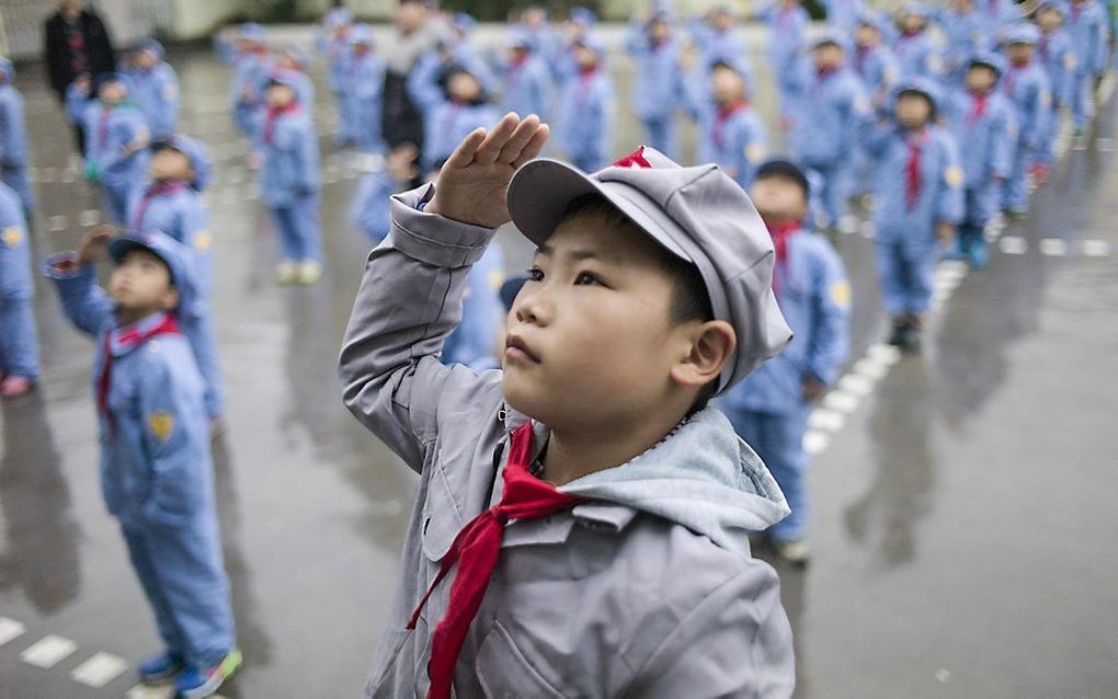 Chinese kinderen krijgen les in de begroetingsceremonie van de vlag. beeld AFP