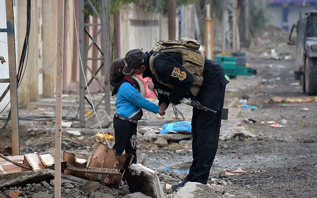 Een Iraakse militair kust een kind in Mosul. beeld AFP