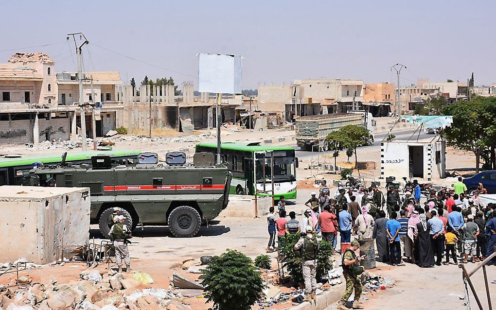 Ontheemde Syrische gezinnen wachten op vervoer.            beeld AFP