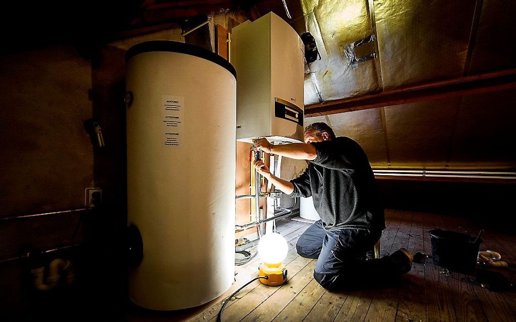 Installatie van een warmtepomp bij een verwarmingsketel (archieffoto). Nuon en Eneco gaan binnenkort op grote schaal warmtepompen verkopen die warmte uit de ventilatielucht van de woning halen. beeld ANP, Koen van Weel