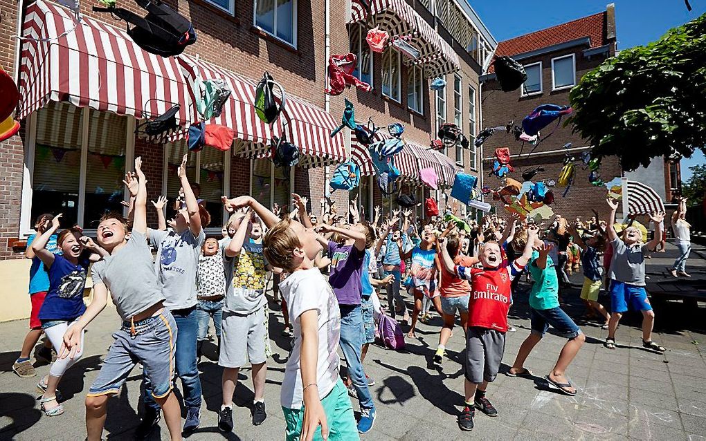 Leerlingen van basisschool Statenkwartier gooien gezamenlijk hun tas in de lucht bij het inluiden van de zomervakantie. beeld ANP