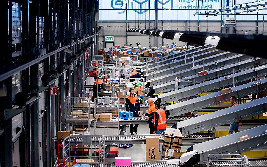 Medewerkers sorteren pakketten in een sorteer- en distributiecentrum van PostNL in Waddinxveen. beeld ANP