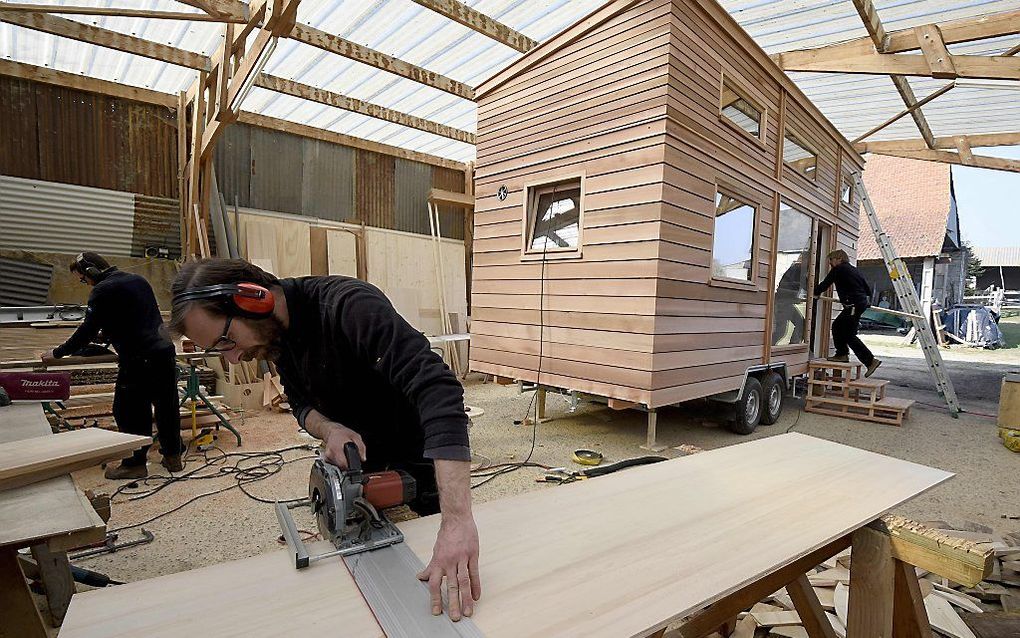 Een traditioneel tiny house staat op wielen en is zo klein dat je het met een trekhaak kunt verplaatsen. Foto: tiny house in aanbouw in een werkplaats in Frankrijk. beeld AFP Damien Meyer