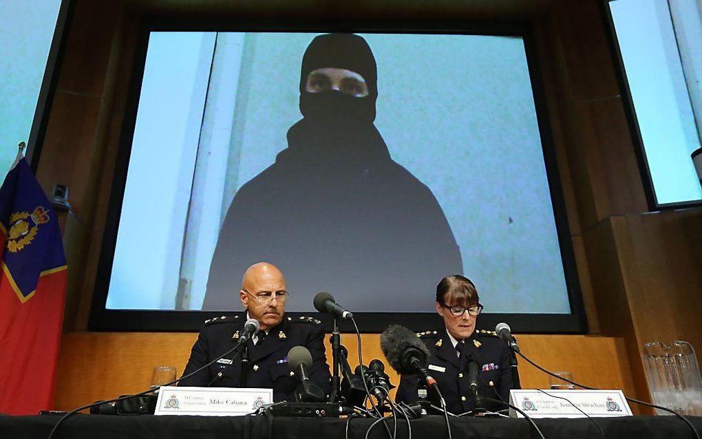 Persconferentie met op de achtergrond een foto van de verdachte. beeld AFP