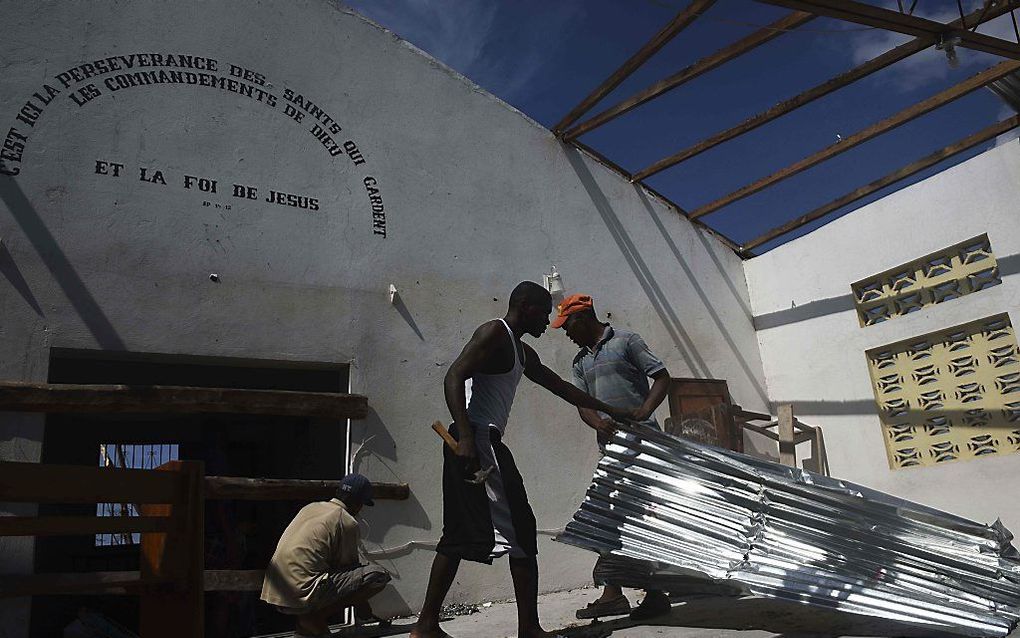 Inwoners van Port-Salut in Haïti voeren herstelwerkzaamheden uit aan de plaatselijke kerk. beeld AFP