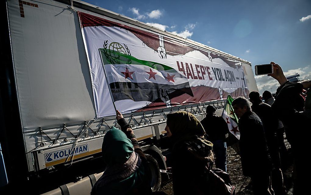 Een vrouw zwaait woensdag met een Syrische vlag terwijl een hulpkonvooi vanuit Istanbul vertrekt naar Aleppo. beeld AFP