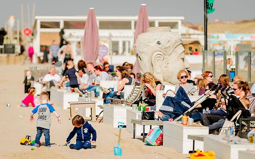 Mensen genieten van het lekkere weer op het strand van Kijkduin tijdens een stralende lentedag. beeld ANP