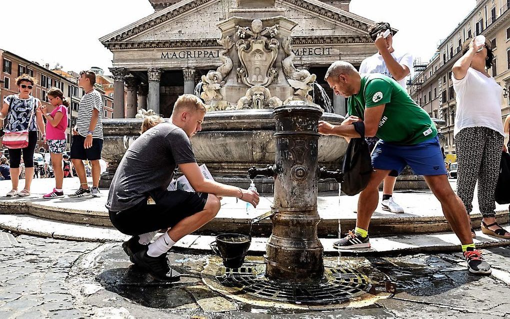 Toeristen drinken water uit een fonteintje in Rome. beeld AFP