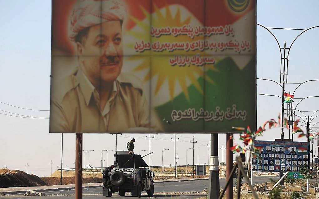 Iraakse troepen bij een billboard met daarop een afbeelding van de Koerdische leider Massoud Barzani. beeld AFP