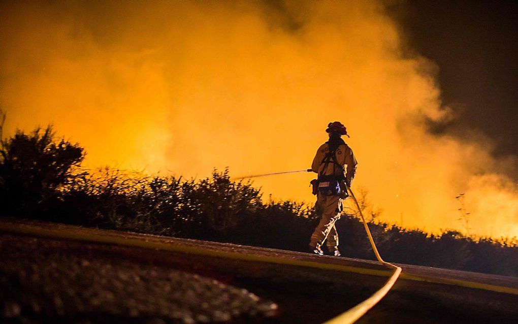 Een brandweerman bestrijdt de vlammenzee bij Los Angeles. beeld AFP