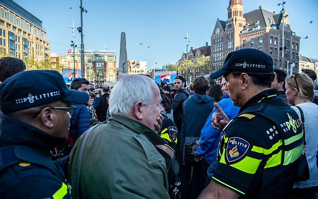 Een man met een spandoek wordt gearresteerd bij de Nationale Dodenherdenking op de Dam. Op het spandoek stond de tekst Churchill Massamoordenaar. beeld ANP