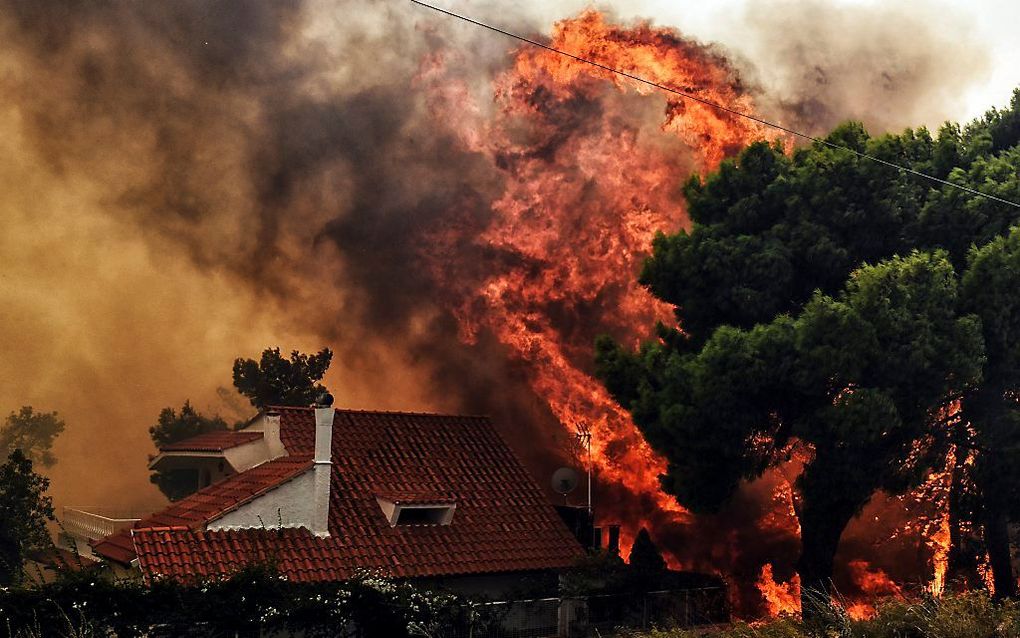 Een huis wordt bedreigd door het vuur in Kineta, bij Athene. beeld AFP