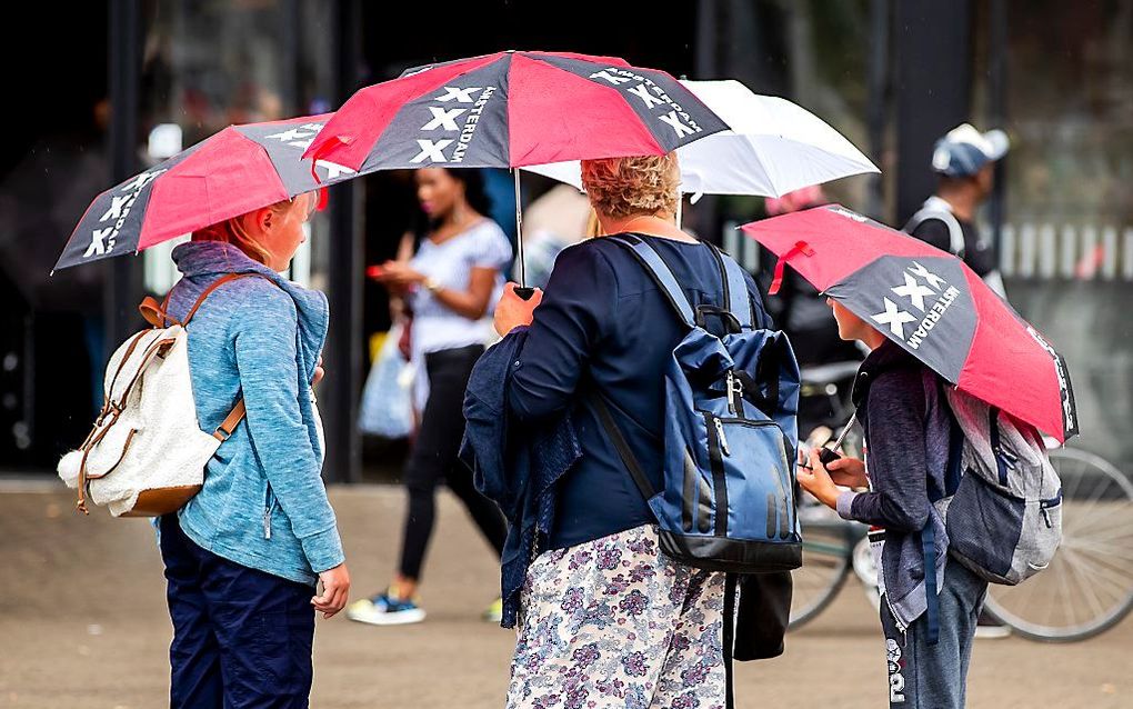 Toeristen en Amsterdammers in de regen. beeld ANP