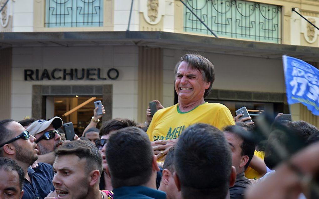 Jair Bolsonaro grijpt naar zijn buik terwijl zijn gezicht is vertrokken van de pijn. beeld AFP