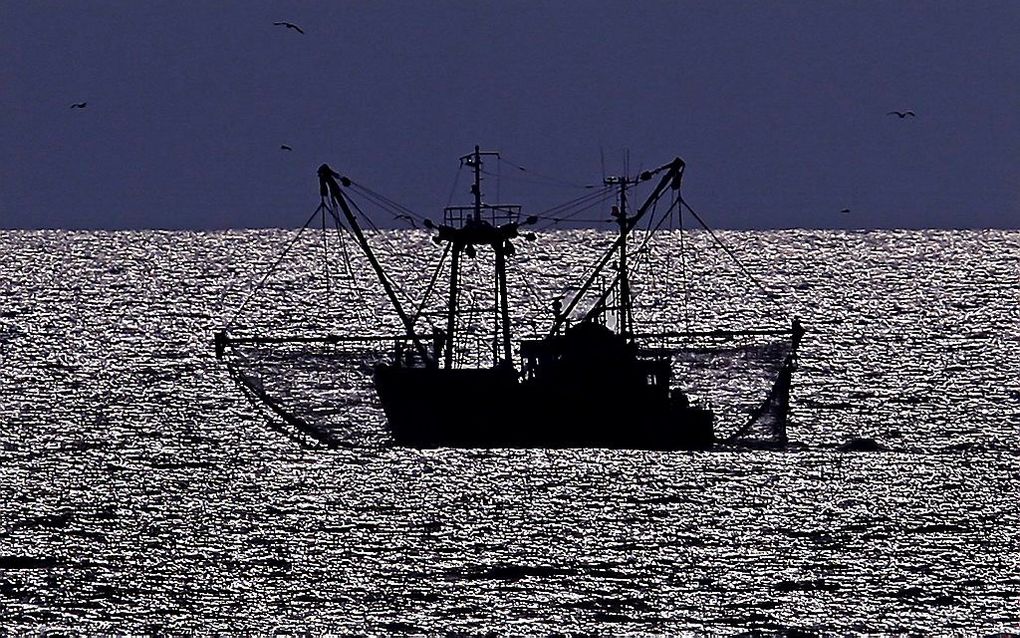 Een viskotter vaart, terwijl de zon langzaam ondergaat, langs de Katwijkse kust. beeld ANP, Olaf Kraak