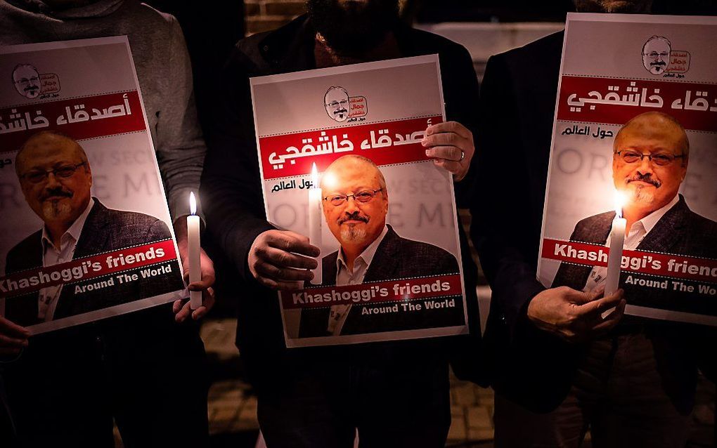 Betogers houden posters met de afbeelding van Khashoggi omhoog bij het consulaat van Saoedi-Arabië in Istanbul. beeld AFP