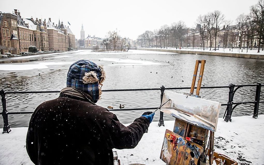 Een man schildert bij de Hofvijver in Den Haag. beeld ANP