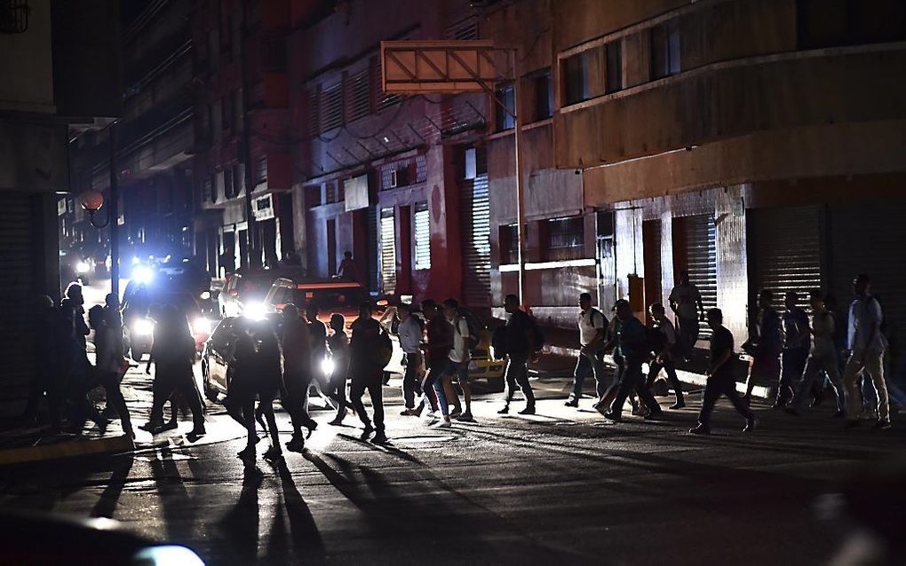 Mensen steken een straat over tijdens een stroomstoring in Caracas op 7 maart 2019. beeld AFP