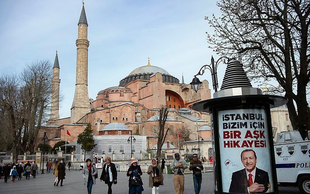 Mensen lopen langs een verkiezingsposter van de Turkse president Erdogan, afgelopen dinsdag. Op de achtergrond de Hagia Sophia, Istanbul. beeld AFP