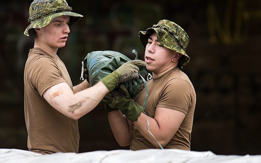 Canadese militairen zijn in de weer met zandzakken in de plaats Laval. beeld AFP