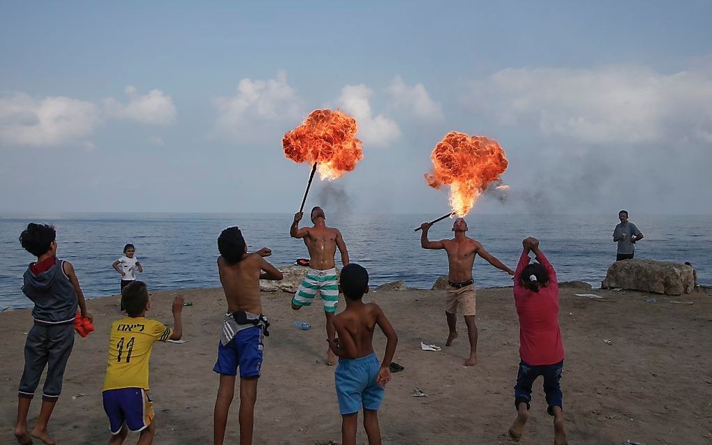 Vuurspuwers vermaken kinderen op het strand van Gaza-stad. beeld AFP