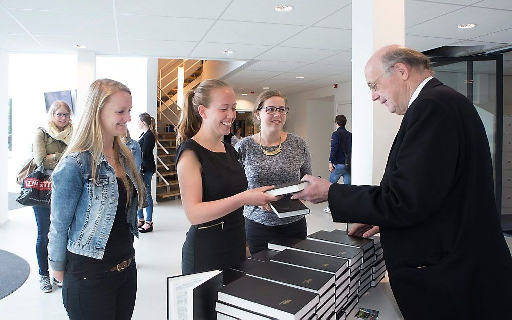 Ds. A. C. Rijken van de Gereformeerde Bijbelstichting (GBS) overhandigt een Bijbel in de Statenvertaling aan een studente van de Christelijke Hogeschool in Ede. beeld Herman Stöver