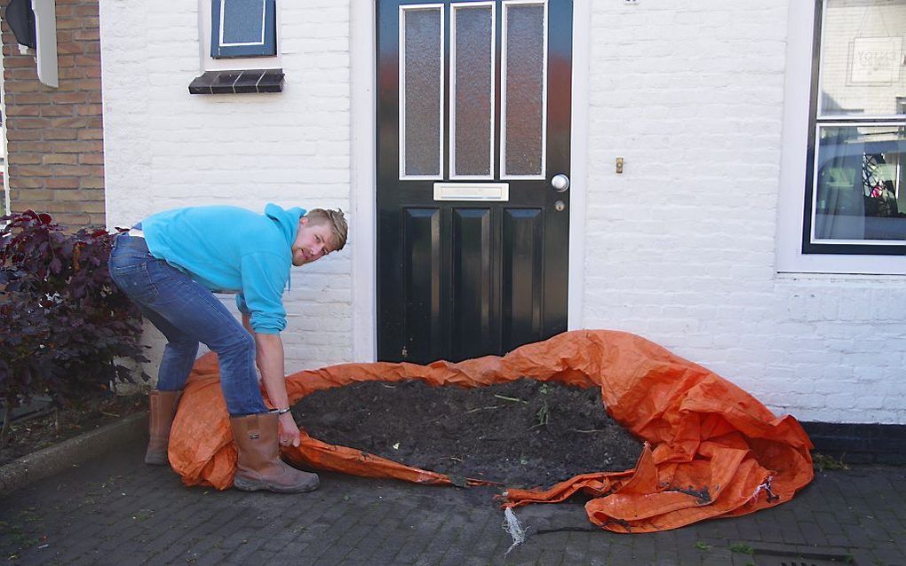 Een inwoner van ’s-Gravenpolder haalt maandagochtend de zandzakken weg waarmee hij zondagavond zijn woning beschermde tegen het water. beeld Van Scheyen Fotografie