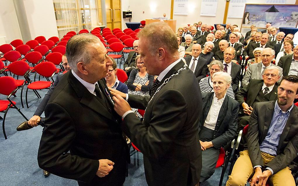 Burgemeester S. Heldoorn (r.) van de Friese gemeente Dantumadeel speldt ds. L. H. Oosten de versierselen op behorend bij zijn onderscheiding tot ridder in de Orde van Oranje-Nassau. beeld RD, Anton Dommerholt