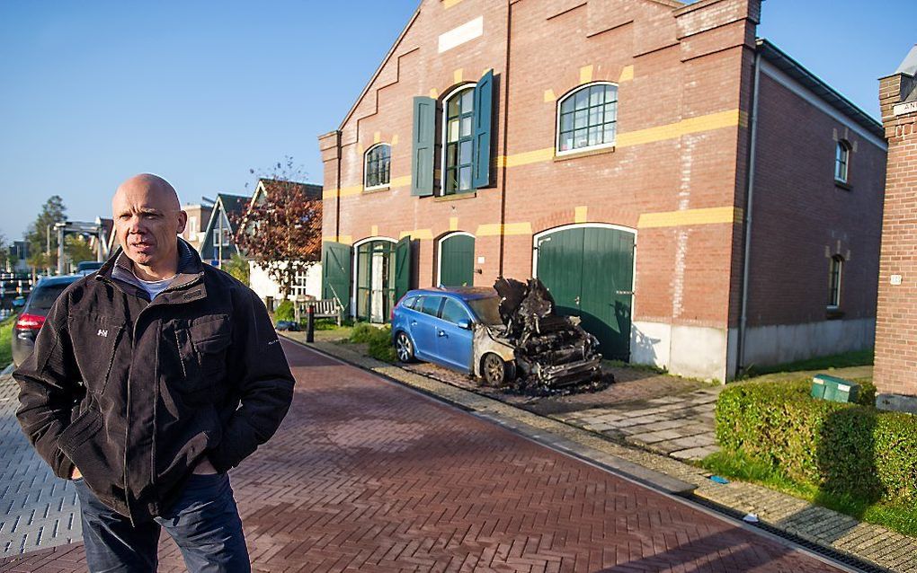 GroenLinks-fractievoorzitter Harold Halewijn nabij een van de twee in brand gestoken auto's. Beeld ANP