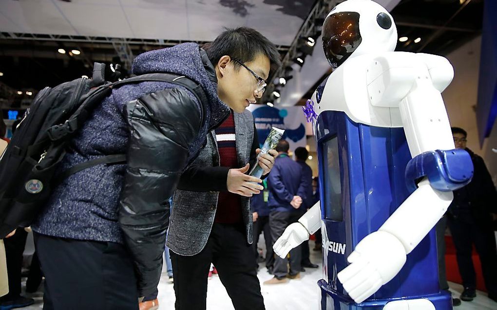 Een bezoeker bekijkt een van de vele robots op de World Robot Conference in Peking. beeld EPA