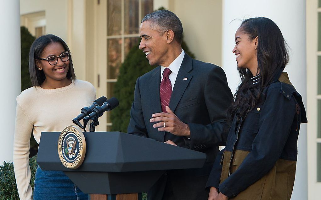 Obama verleent gratie aan een kalkoen. Zijn dochters luisteren mee. Beeld AFP