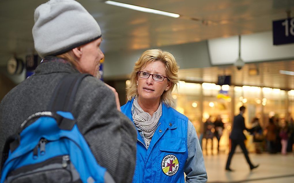 Een medewerker van de Bahnhofsmission in gesprek, in dit geval op station Düsseldorf. Beeld Werner Krüper